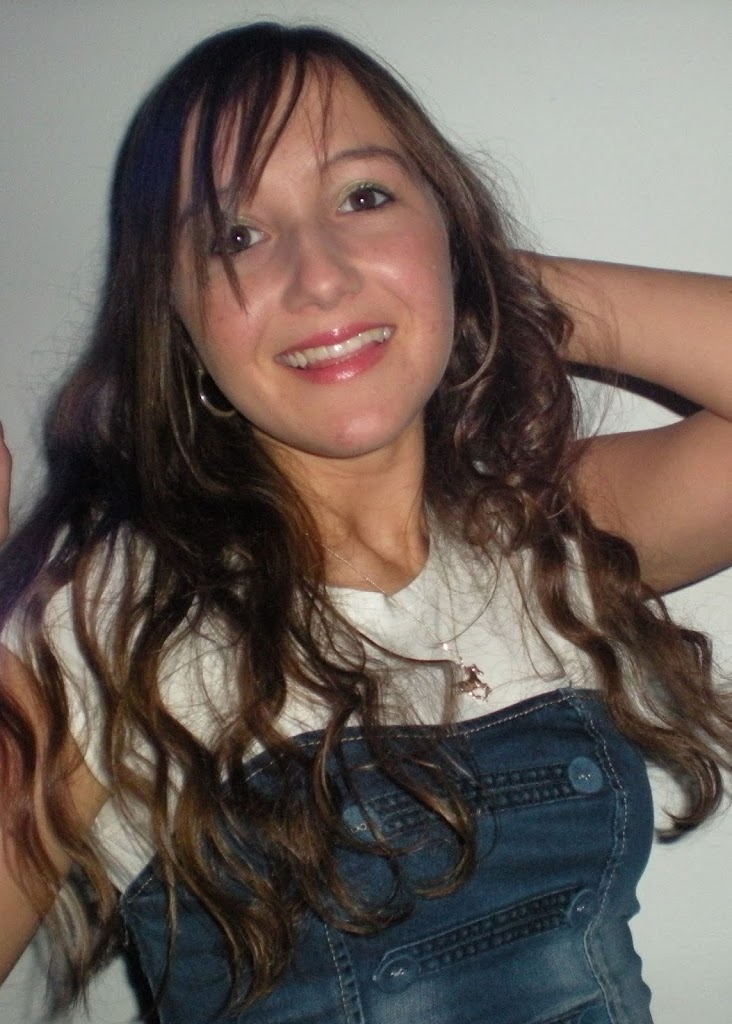 Smiling woman with long brown hair in a denim dress, posing against a plain white background.