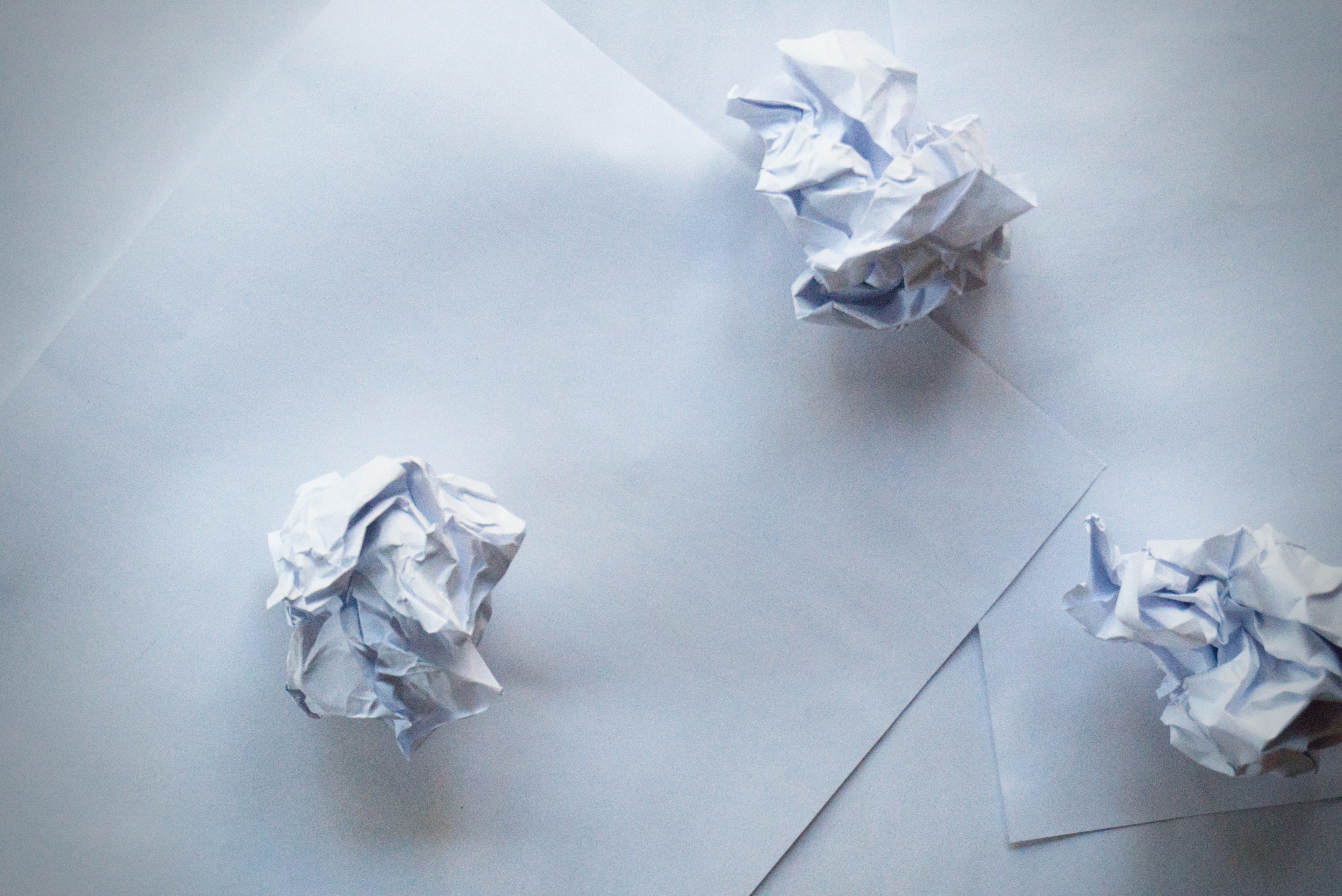 Crumpled paper balls on white sheets, symbolising creativity, brainstorming, and the writing process.