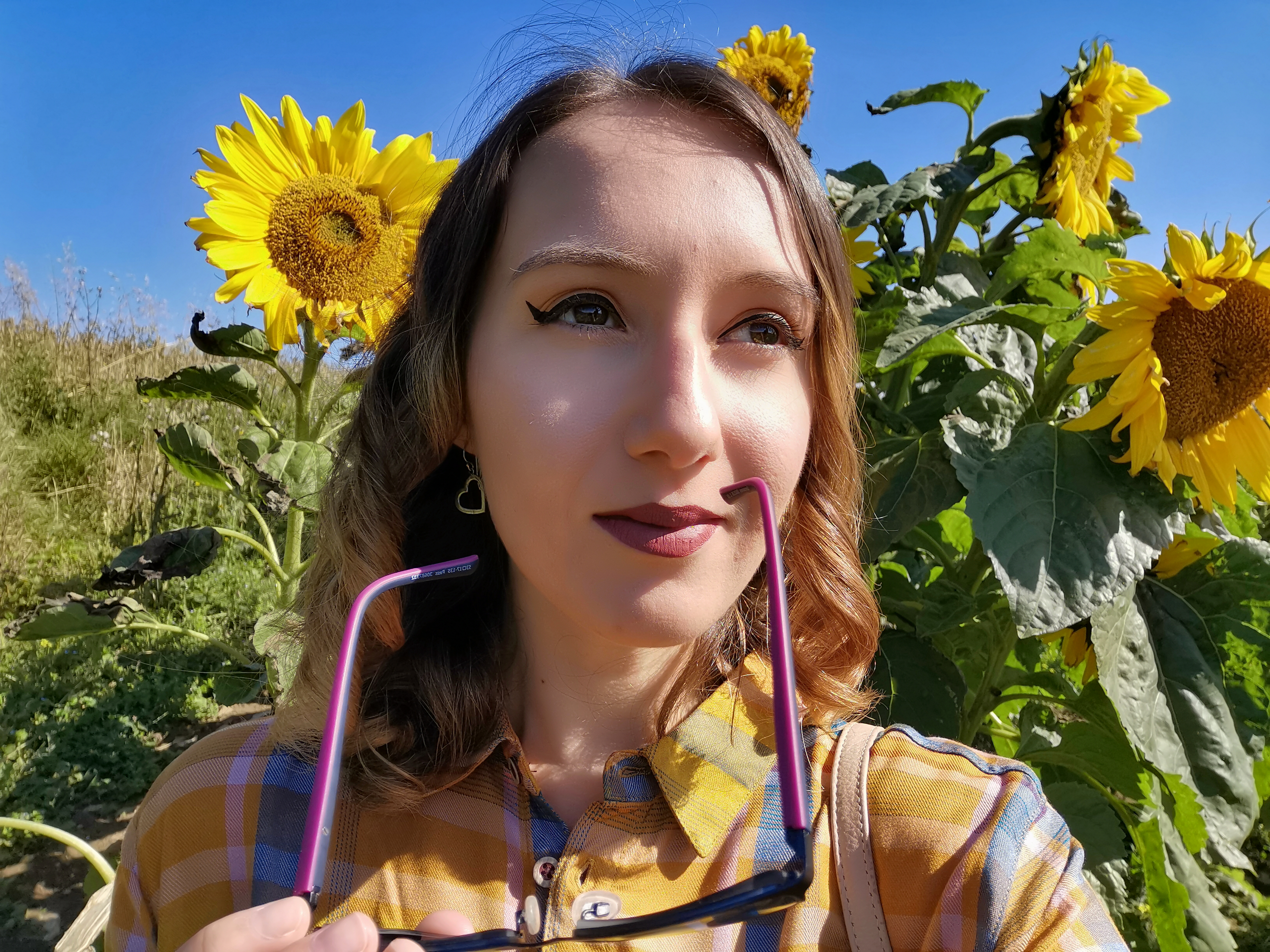 Woman in sunflower field holding glasses, enjoying sunny day. Summer vibes, nature background, vibrant sunflowers.