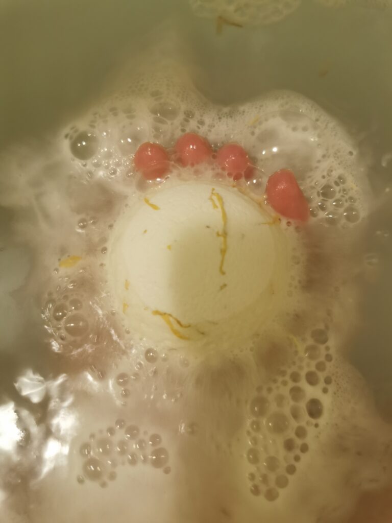 White bath bomb fizzing in a tub with foam and bubbles, creating a soothing bath experience.
