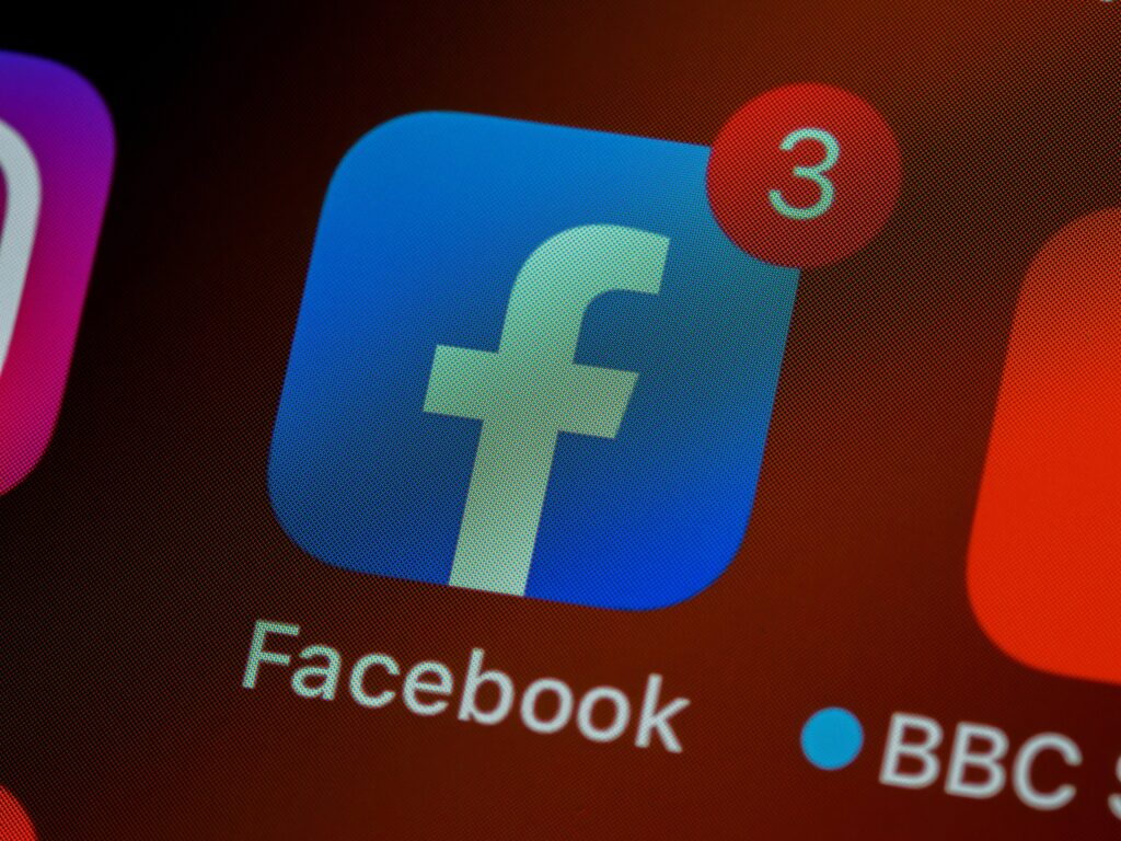 Facebook app icon with three notifications on a smartphone screen, highlighting social media activity.