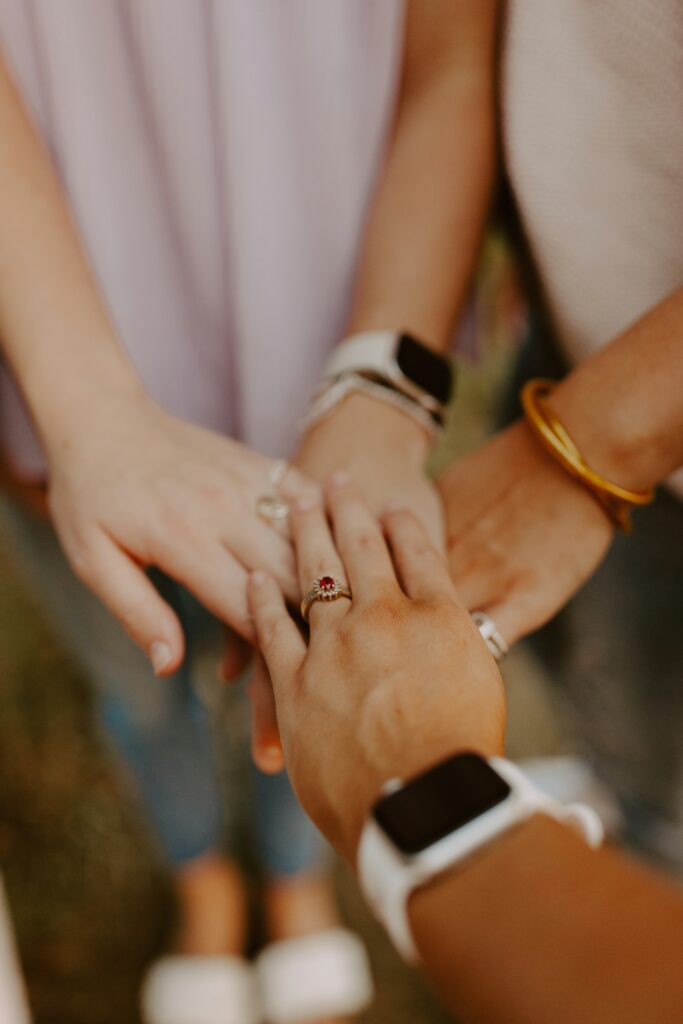 Three hands overlapping, showcasing unity and friendship. Smartwatches and rings highlight modern accessories.