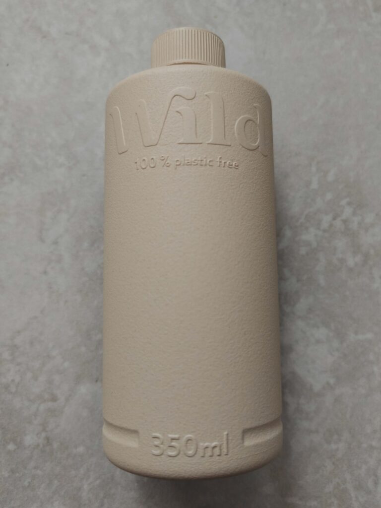 Eco-friendly 350ml bottle, beige, labelled Wild and 100% plastic-free, on a grey textured background.