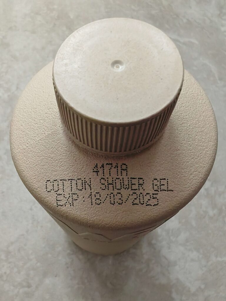 Close-up of a bottle top displaying cotton shower gel with expiry date 18/03/2025.