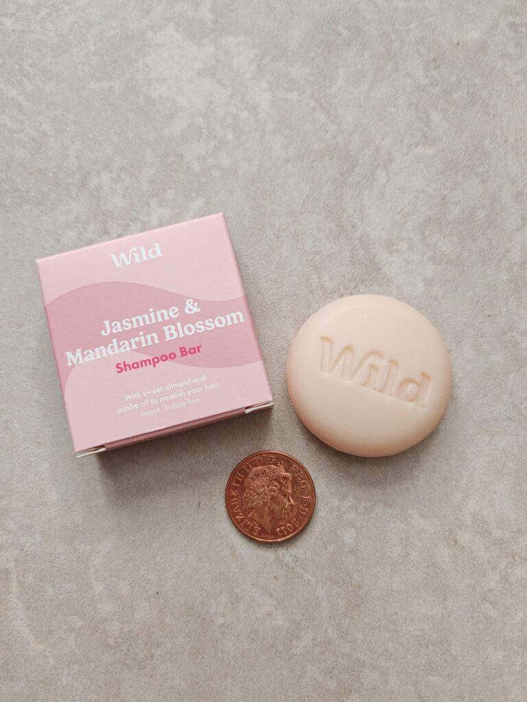 Jasmine & Mandarin Blossom shampoo bar with packaging and a UK penny for scale, displayed on a light surface.