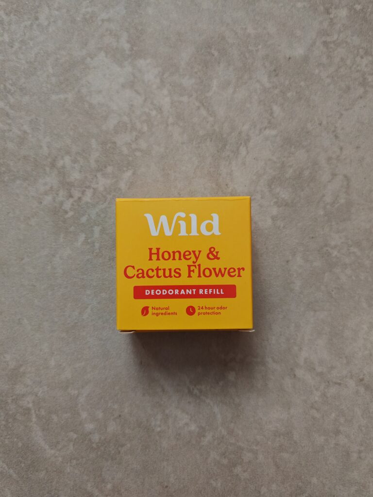 Bright yellow Wild deodorant refill box with Honey and Cactus Flower scent on a textured surface.