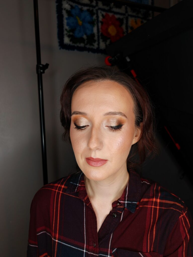 Woman in plaid shirt with closed eyes and polished makeup, under studio lighting.