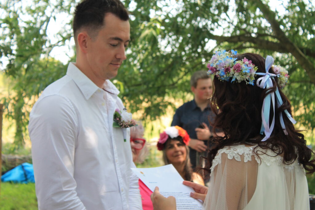 Couple exchanging vows outdoors at a romantic wedding ceremony, adorned with floral decorations.