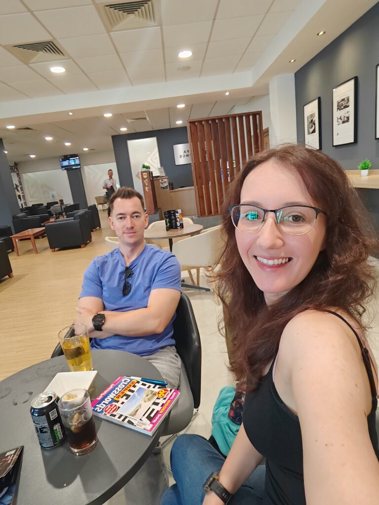 Two people enjoying drinks and magazines at an airport lounge, with a relaxed atmosphere and contemporary decor. Cardiff Airport