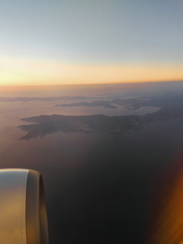 Aerial view of islands at sunset with an aeroplane engine visible, capturing the serene beauty from above.