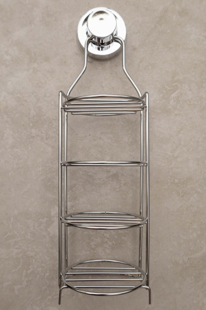 Three-tier chrome shower caddy on a beige background, ideal for bathroom storage and organisation.