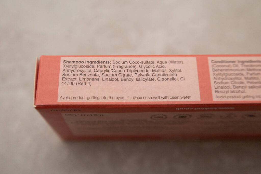 Close-up of a shampoo ingredients list with safety advice on a pink package.