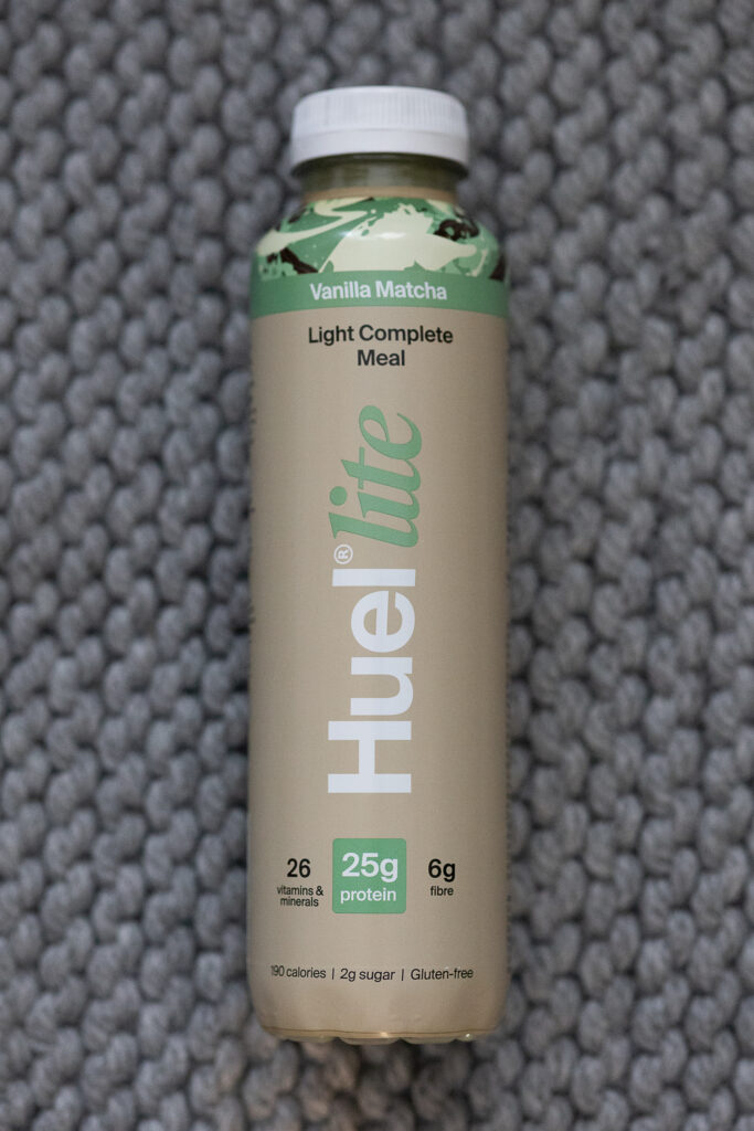 Huel Lite Vanilla Matcha complete meal bottle on textured background. High protein, gluten-free, low calorie drink.