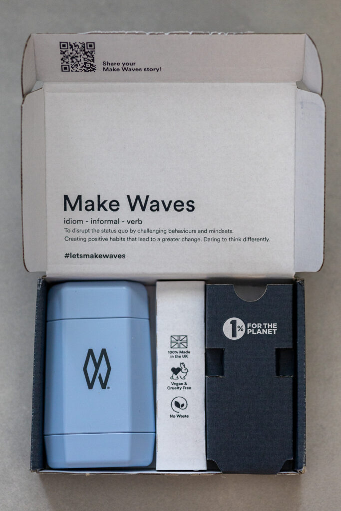 Eco-friendly packaging of a blue Make Waves product with sustainability stickers. UK made and 1% for the planet.