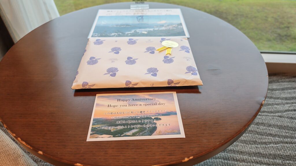 Anniversary gift and card on table, wrapped in floral paper, with scenic postcard, creating a special celebration moment.