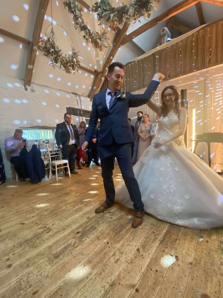 Bride and groom dancing at their wedding reception in a beautifully decorated venue with guests watching.