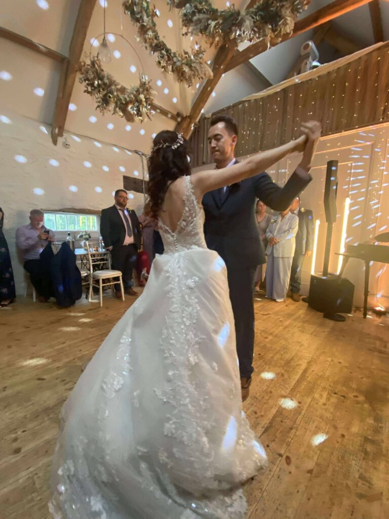 Bride and groom sharing their first dance in a beautifully decorated wedding venue with guests watching.