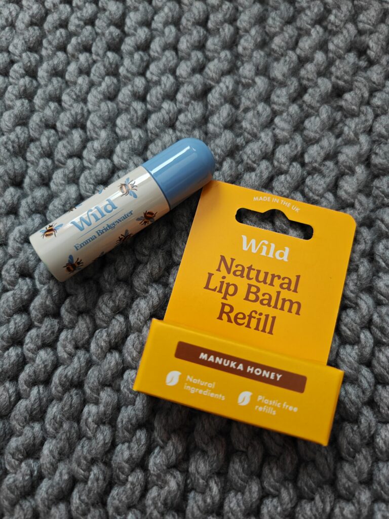 Natural lip balm refill with Manuka honey by Wild on grey textured surface. Eco-friendly, plastic-free UK product.